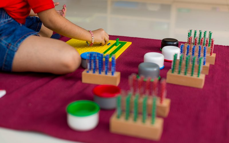 A child at work on a floor mat with Montessori materials at Kidoz Montessori, Chennai.